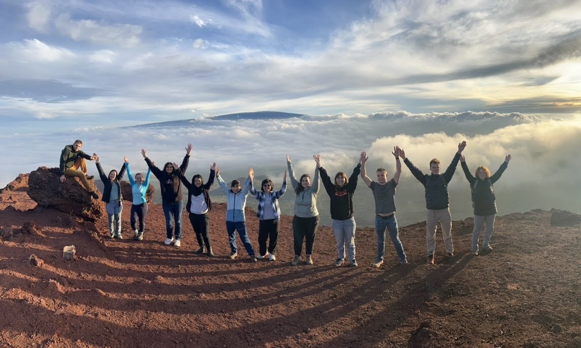 Caltech Y ASB group 9000ft up on the volcano Mauna Kea with Mauna Loa in the distance, surrounded by smaller volcanoes under the clouds
