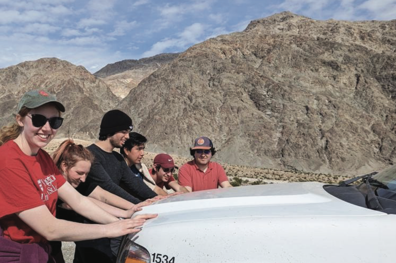 Photo of many students pushing on a car together