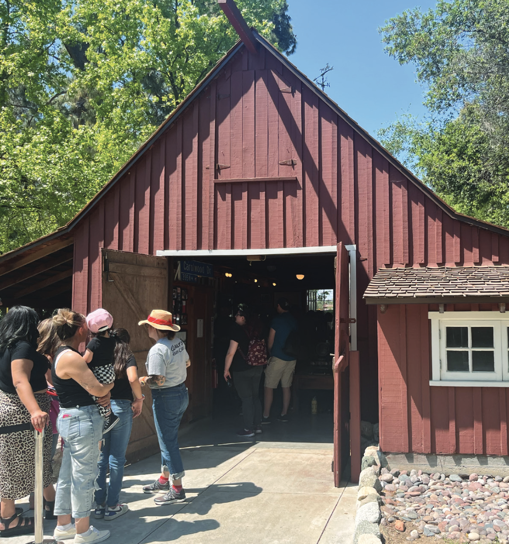 Photo of small gabled barn, people mingling around the open entrance