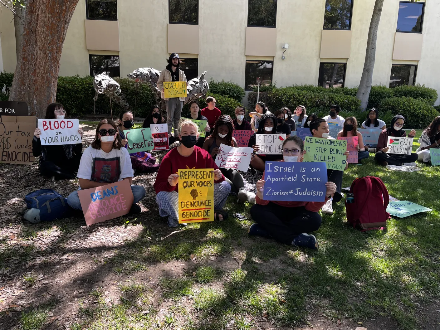 A similar group of protesters sitting outside the Center of Student Services, holding signs reading “Deans: Denounce Genocide,” “Represent Our Voices: Denounce Genocide,” “Israel is an Apartheid State. Zionism doesn’t equal Judaism,” and more