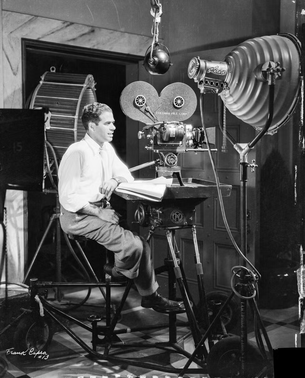 Photo of Frank Capra sitting in front of recording equipment, see description below