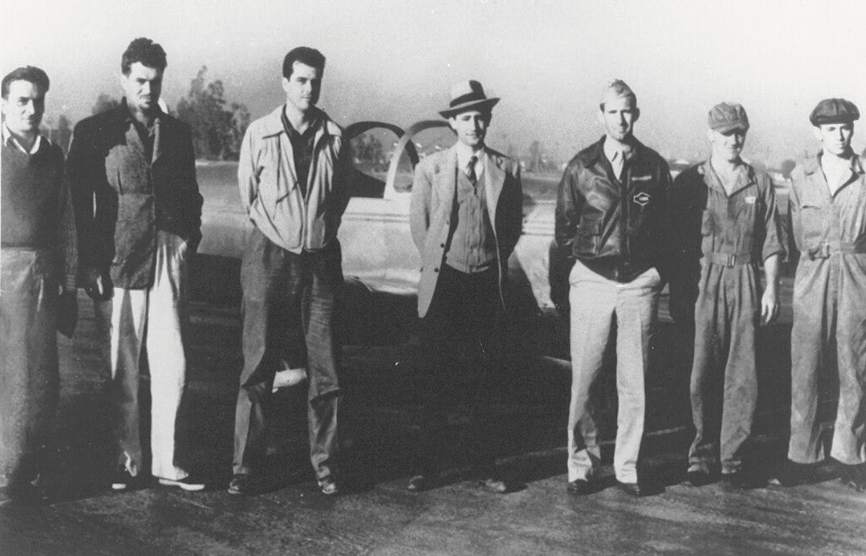 Grayscale photo of a group of people standing in a row for the camera.